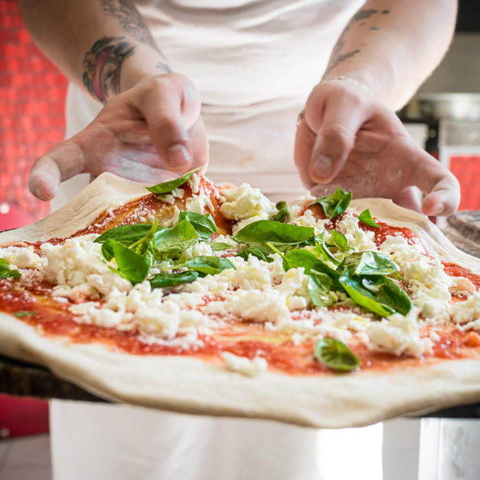 a pair of hands preparing a margherita pizza