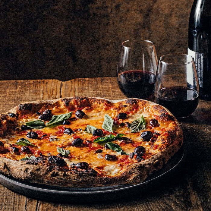 Pizza served on wooden table with red wine
