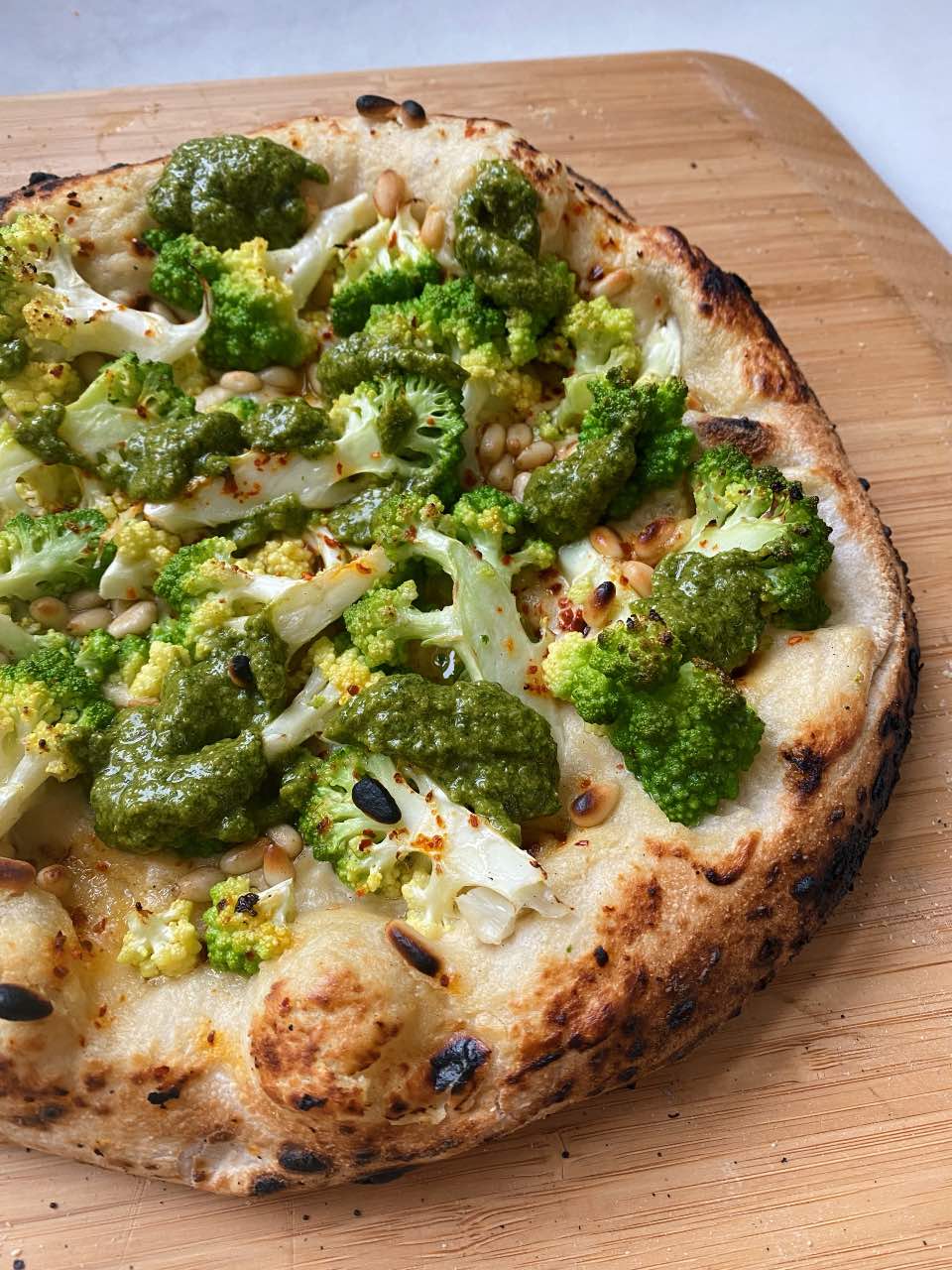 Pizza with creamy cashew cream base, topped with Romanesco cauliflower and a herby Mediterranean salsa verde