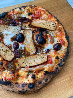 Pizza topped with slices of smoked tofu, caramelised onions, black olives and melted vegan cheddar 