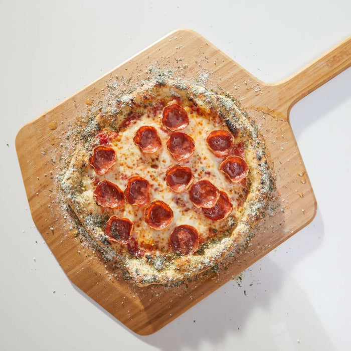 Pizza topped with cheese, pepperoni and ranch crust dust on a wooden pizza peel