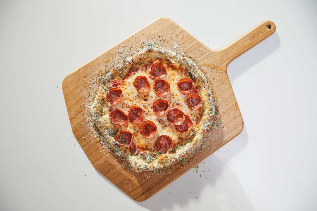 Pizza topped with cheese, pepperoni and ranch crust dust on a wooden pizza peel