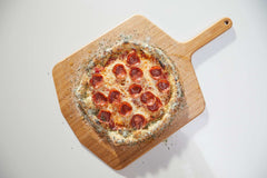 Pizza topped with cheese, pepperoni and ranch crust dust on a wooden pizza peel