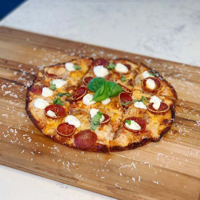 A bar style pizza topped with pepperoni and cheese on a wooden chopping board. Baked with a bar style pizza recipe.