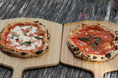 Two pizzas on wooden pizza peels baked using a 100% Biga pizza dough recipe