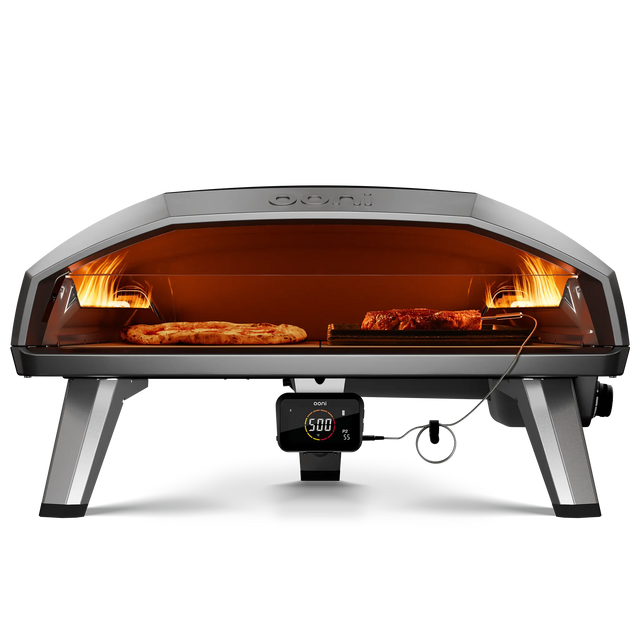 Front view of Koda 2 Max gas powered pizza oven with pizza and meat cooking inside side by side 