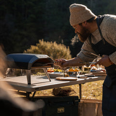 a man using a cast iron skillet with the koda 12 pizza oven