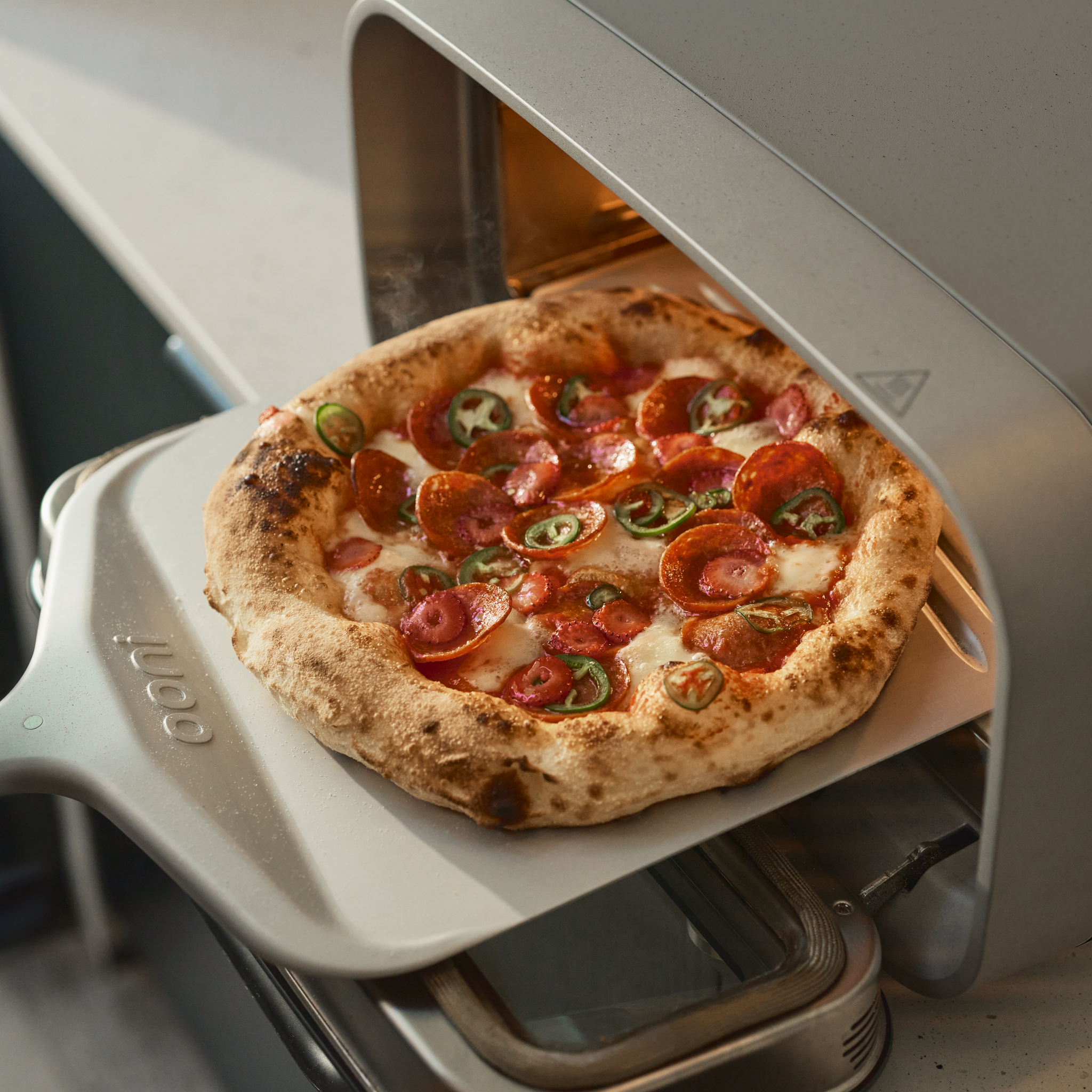pizza being retrieved from ooni volt 2 